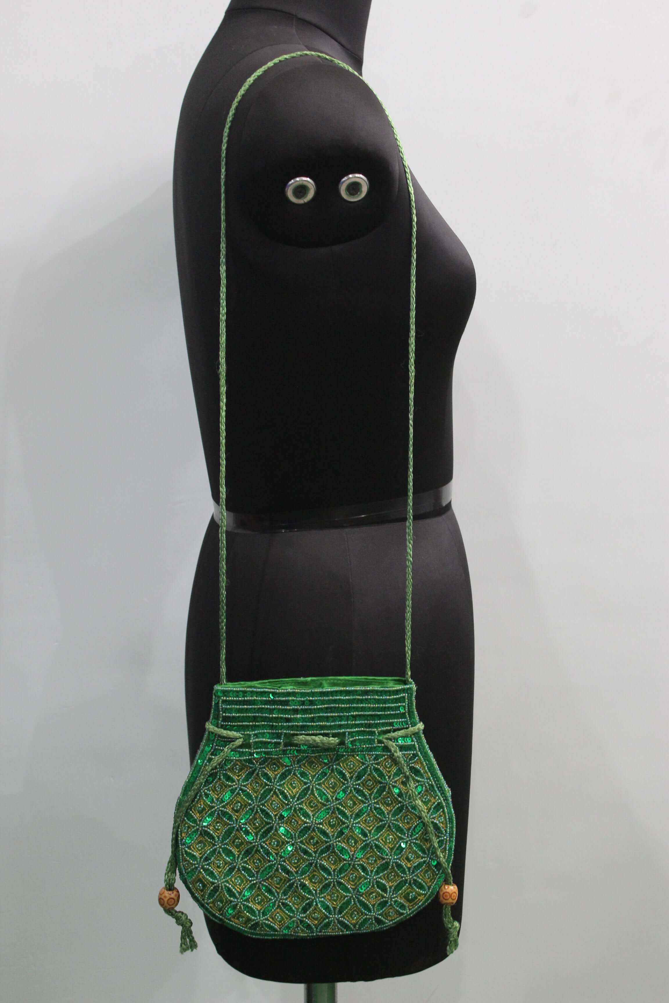 Stylish green handmade Indian potli bag with sequins on display, perfect for carrying small items.